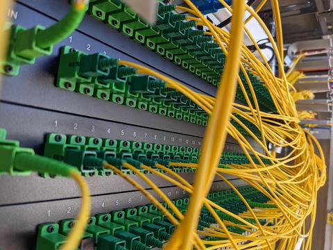 Nærbillede af fiberpatchpanel med gule patchkabler tilsluttet grønne LC-konnektorer